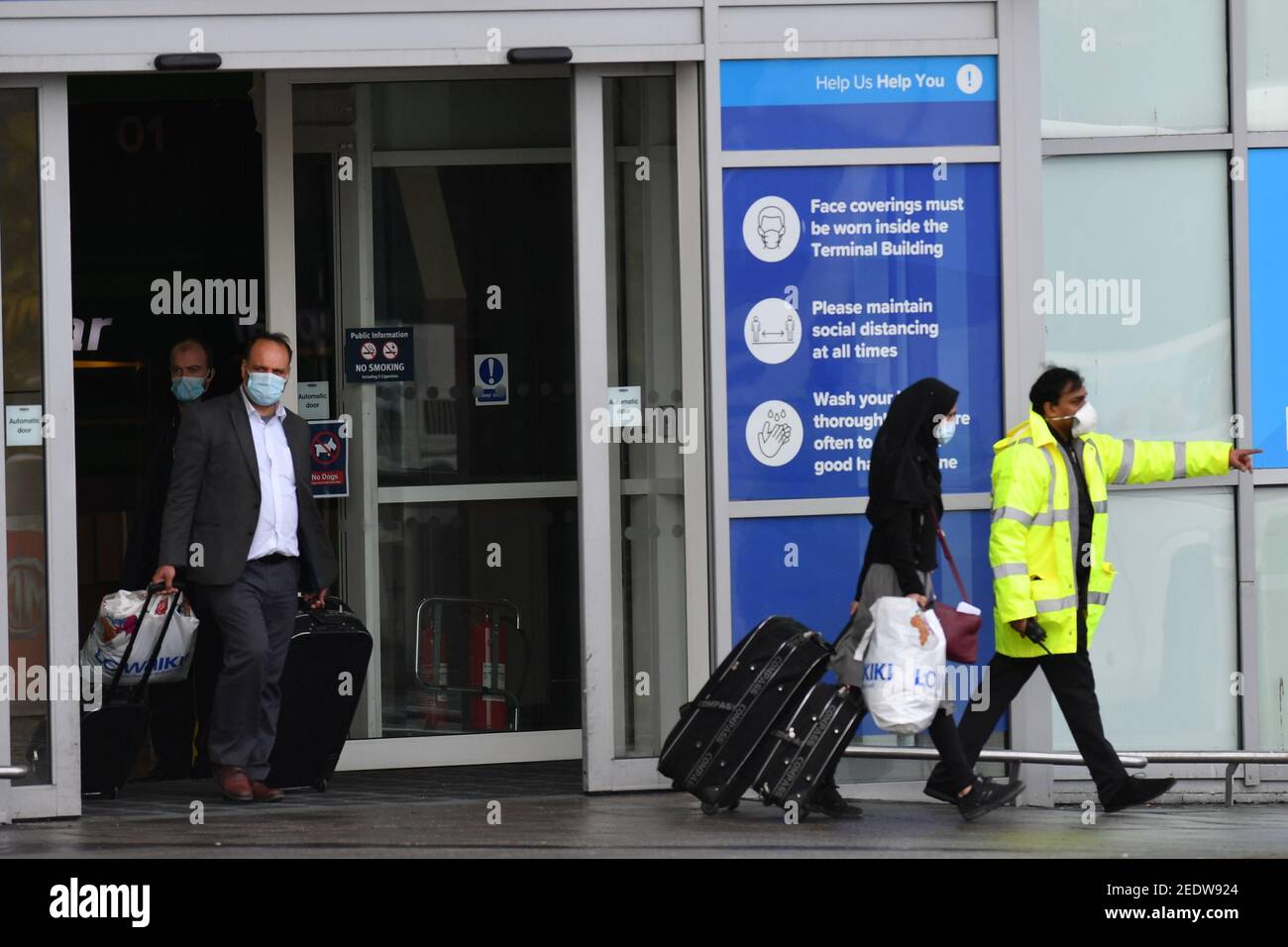 Two passengers leave Birmingham Airport onboard a coach after landing in England. New regulations now in force require anyone who has recently been in a high-risk location to enter England through a designated port and have pre-booked a package to stay at one of the Government's managed quarantine facilities. Picture date: Monday February 15, 2021. Stock Photo