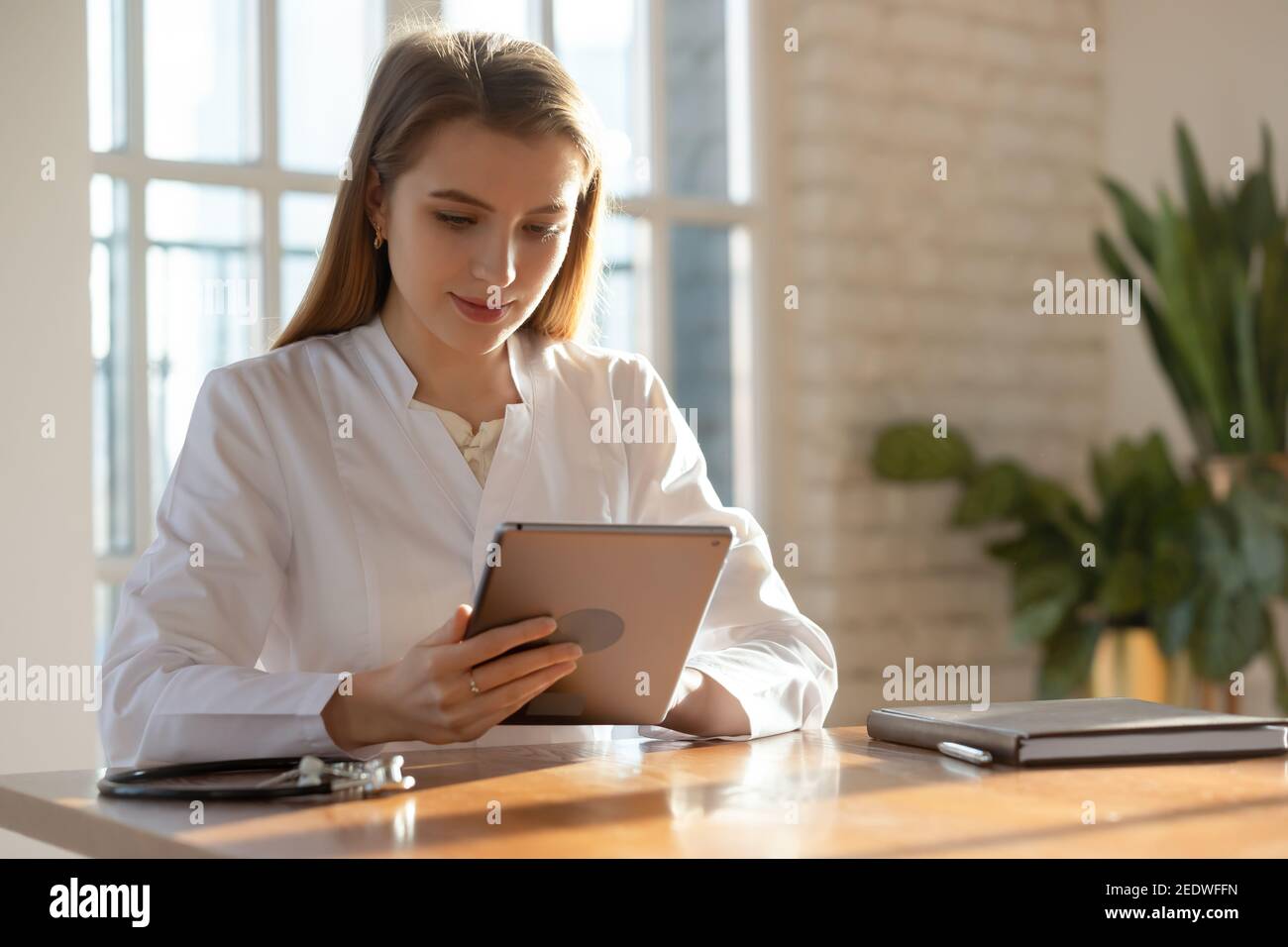 Smiling attractive young female doctor using computer tablet. Stock Photo