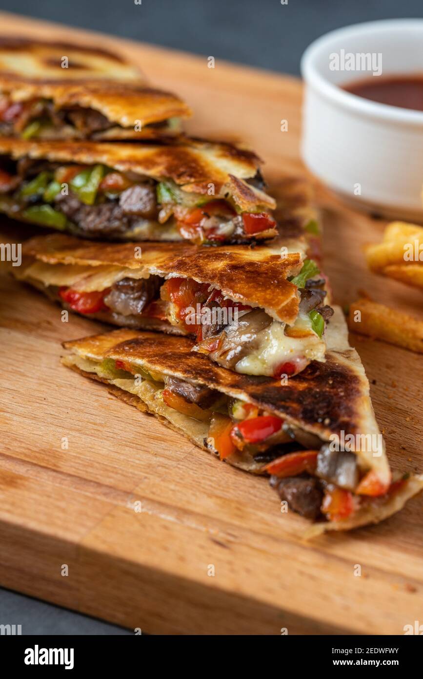 Mexican quesadilla with meat, cheese and peppers on wooden table. Stock Photo