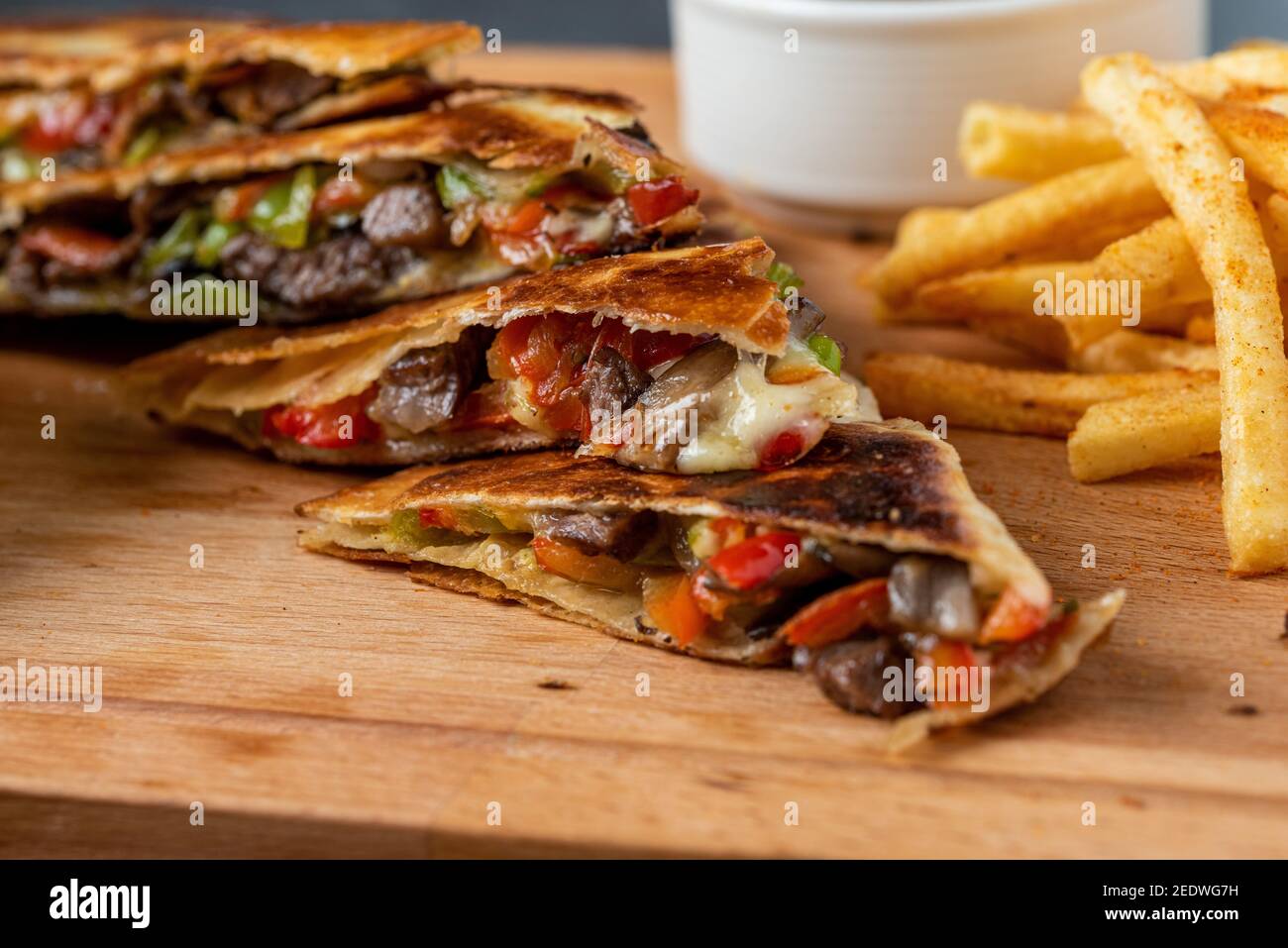 Mexican quesadilla with meat, cheese and peppers on wooden table. Stock Photo