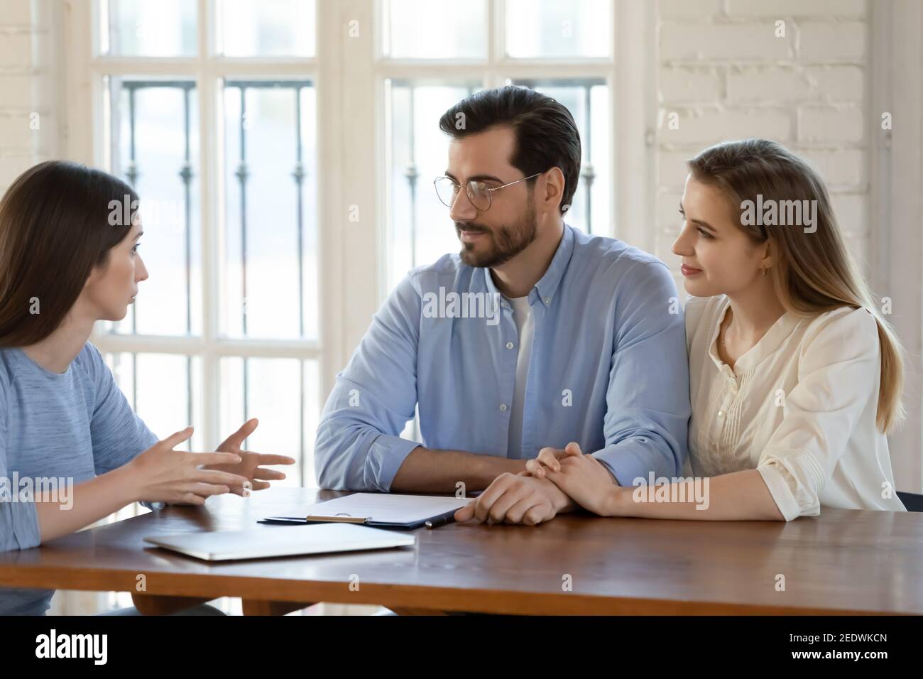 Happy young family couple visiting female real estate agent. Stock Photo