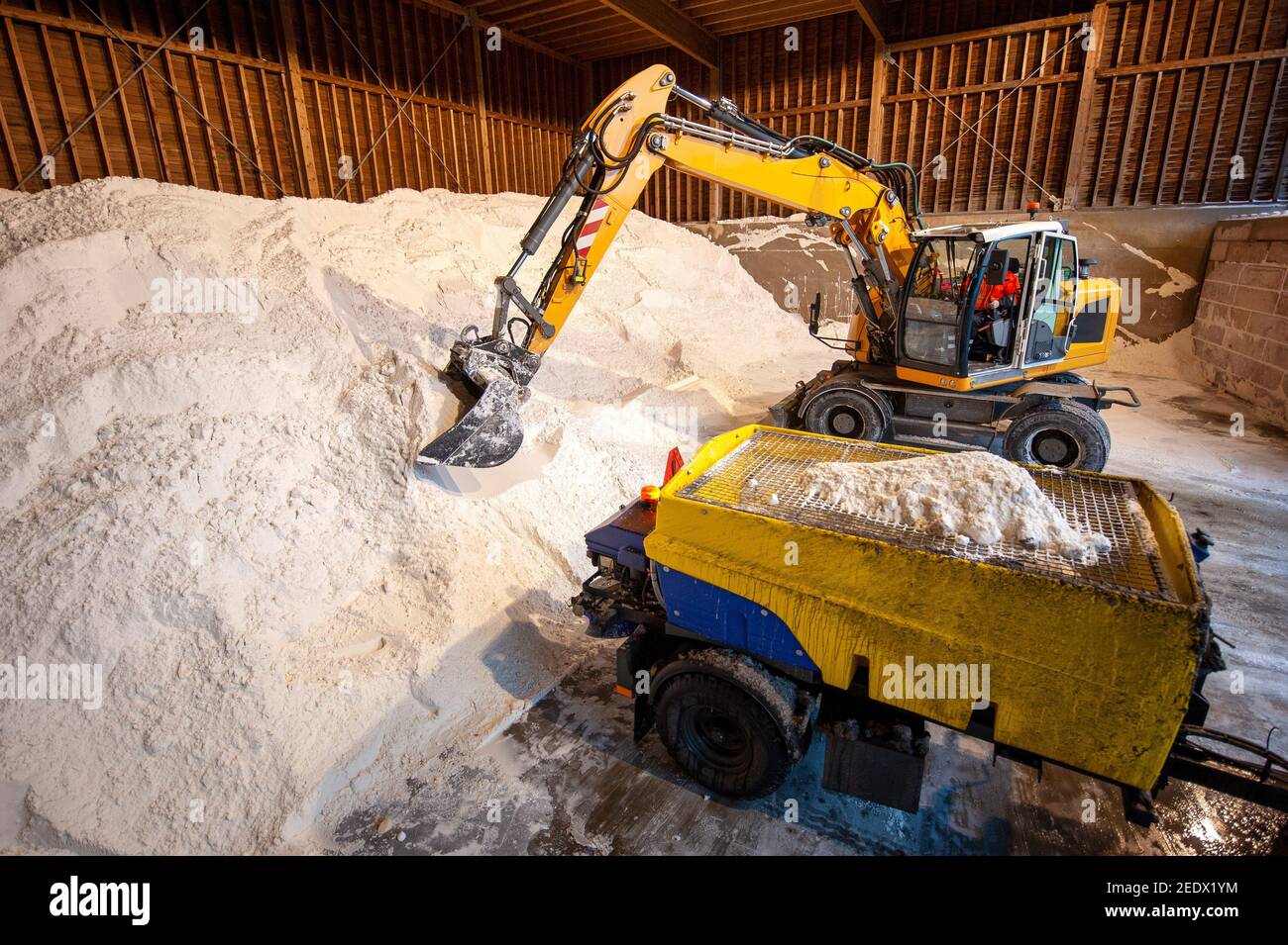 An excavator at work in a salt storage used for anti skidding on a road. Stock Photo