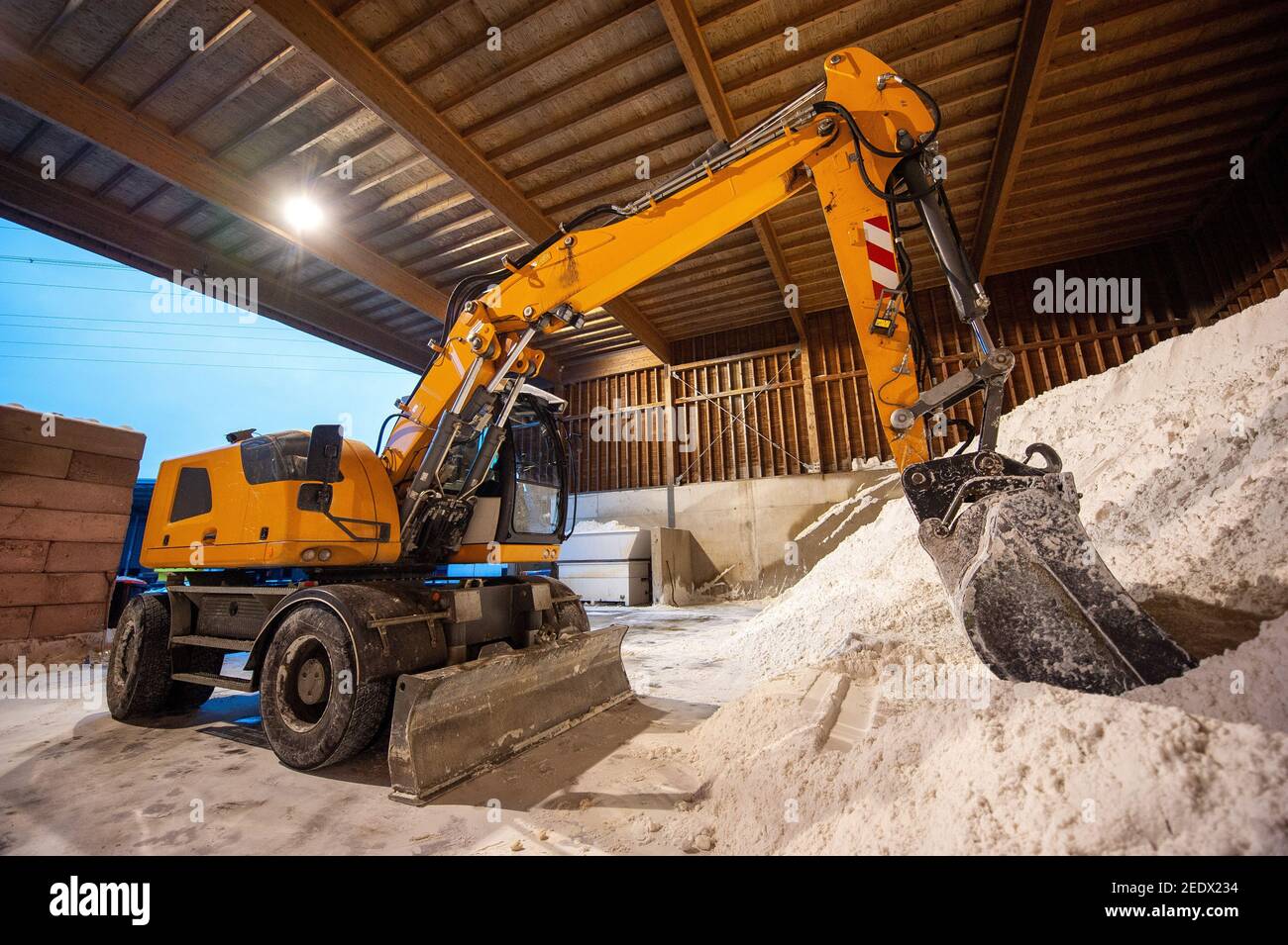 An excavator in a salt storage used for anti skidding on a road. Stock Photo