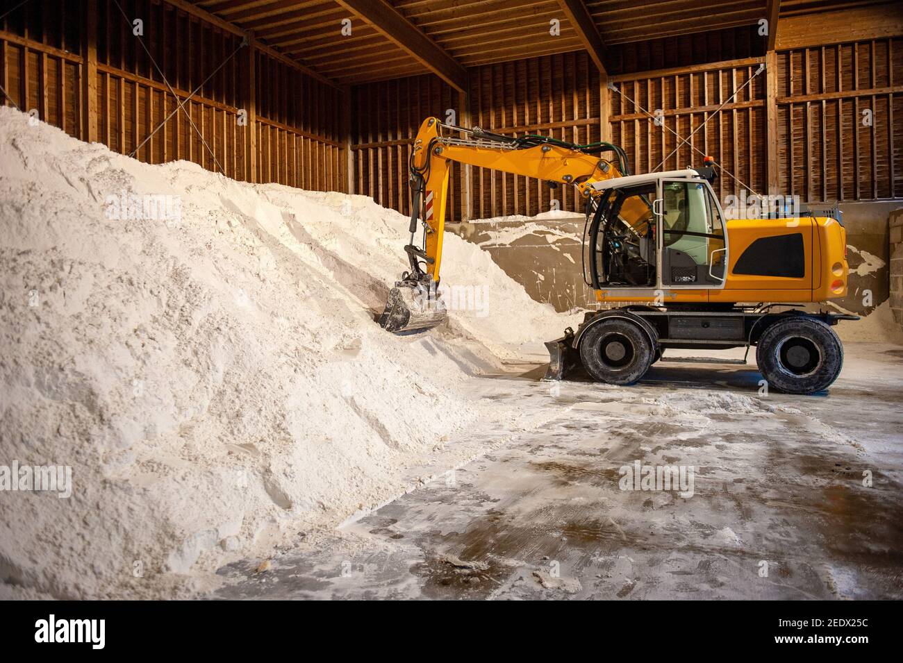 An excavator in a salt storage used for anti skidding on a road. Stock Photo