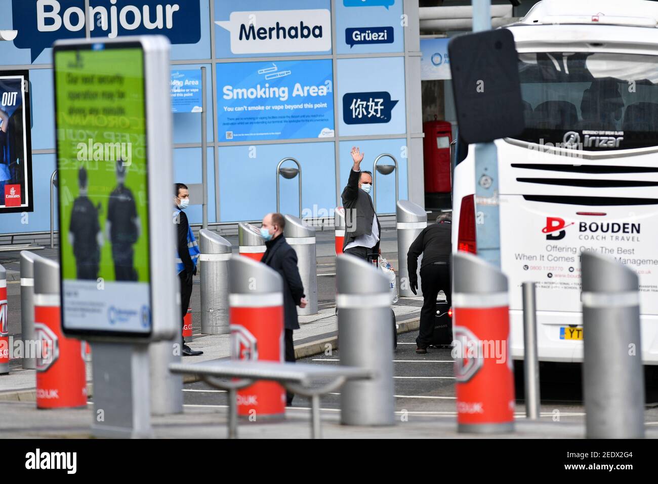 A man waves as he leaves Birmingham Airport onboard a coach after landing in England. New regulations now in force require anyone who has recently been in a high-risk location to enter England through a designated port and have pre-booked a package to stay at one of the Government's managed quarantine facilities. Picture date: Monday February 15, 2021. Stock Photo