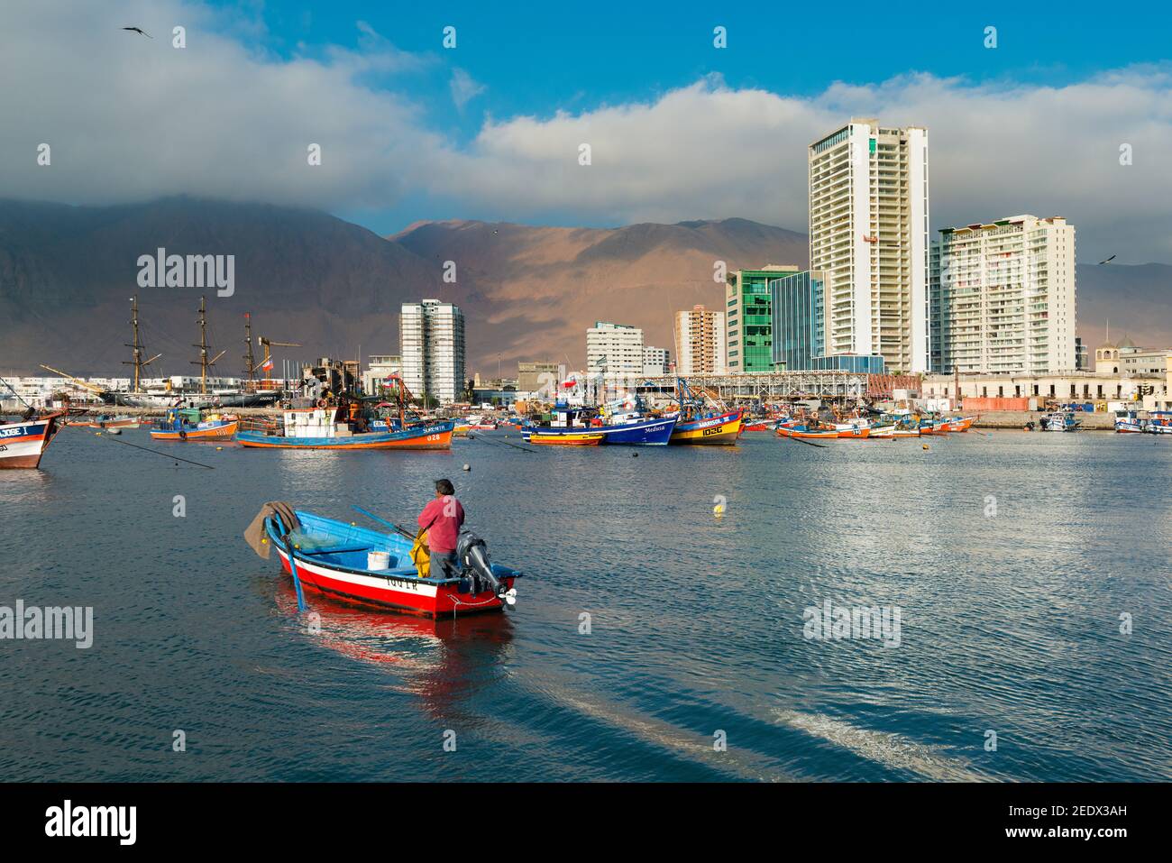 Iquique, Tarapaca Region, Chile - Fisherman in a boat at the marina of Iquique with city skyline in the back. Stock Photo