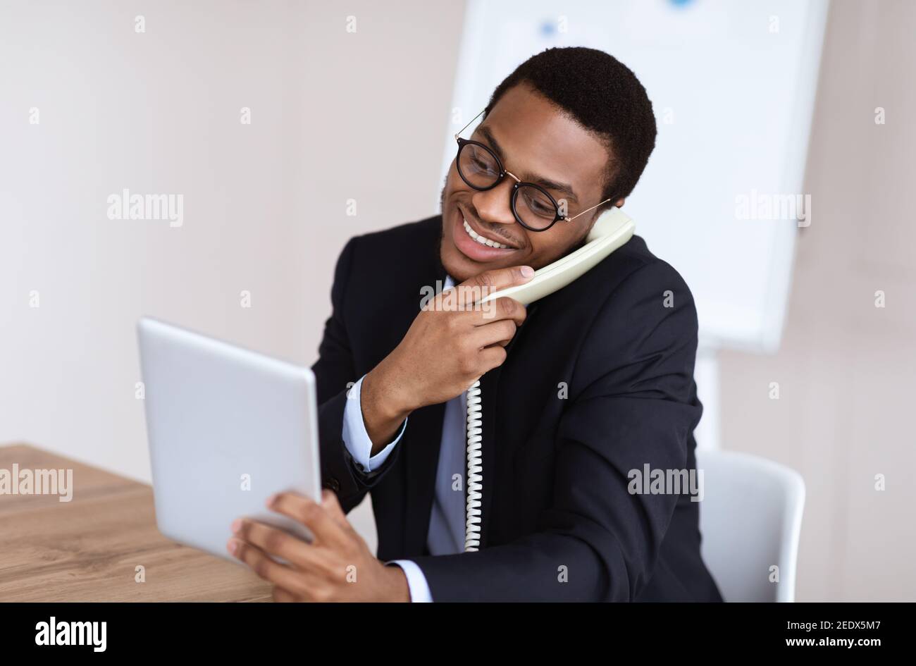 Black man in suit talking on phone, using digital tablet Stock Photo