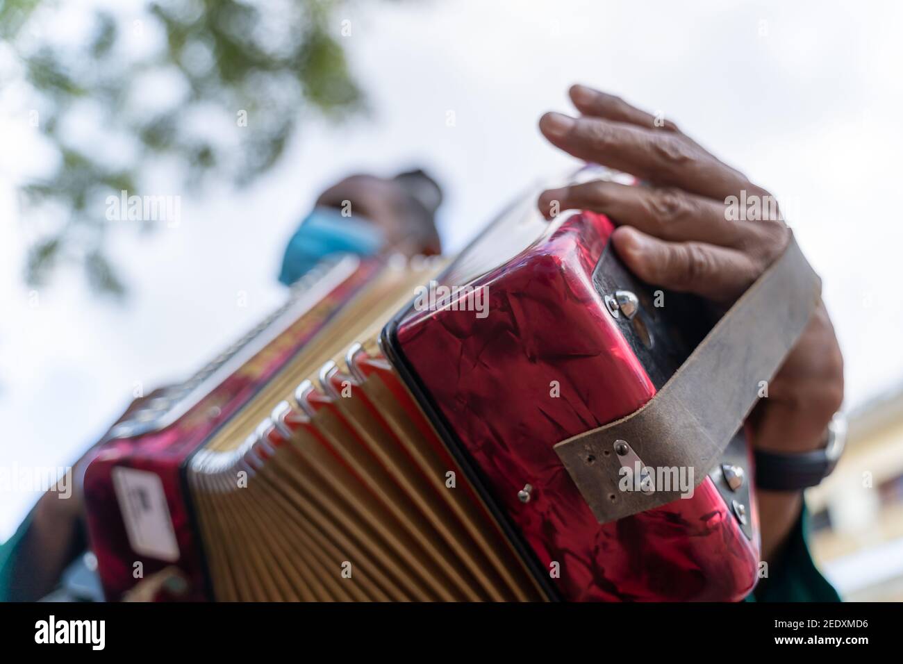 Accordionist wearing a protective face mask playing outdoors Stock Photo