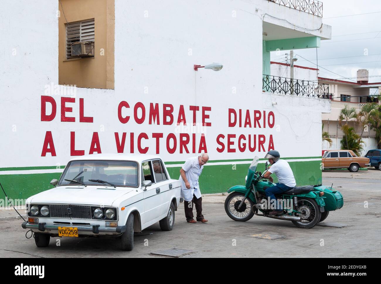 A doctor inflating Lada tires or wheels. Two men see the old soviet car and motorcycles in the streets of the Cuban city. The inscriptio Stock Photo