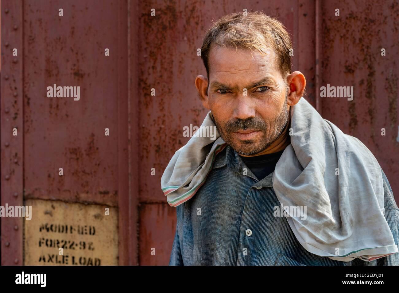 Portrait of man wearing only scarf as protection employed to move bags of cement from train to lorries at Mathura, Uttar Pradesh, India. Stock Photo