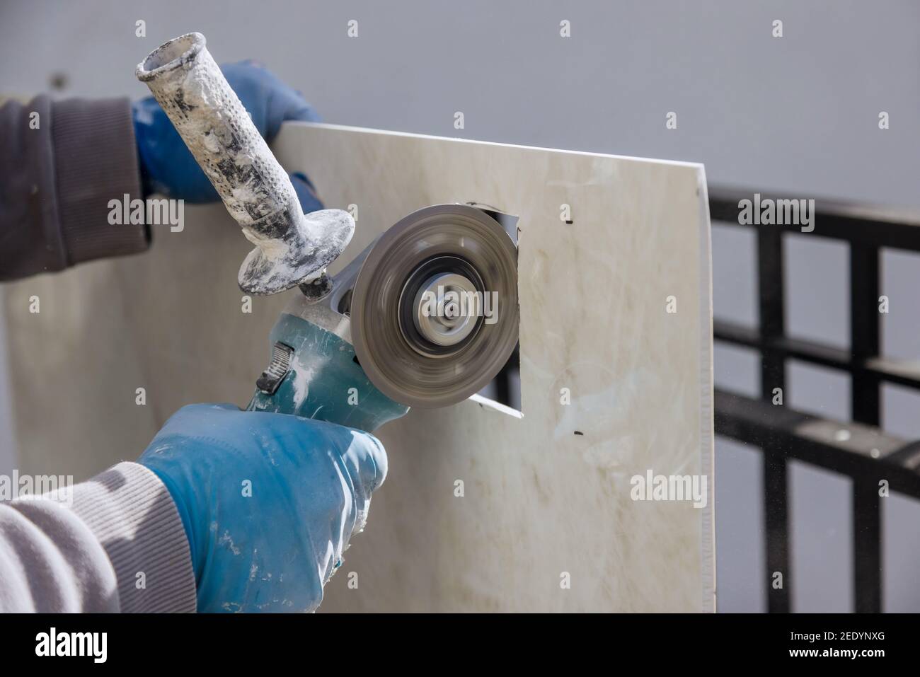 Angle grinder with an cutting ceramic tiles a square opening a hole in the tile Stock Photo