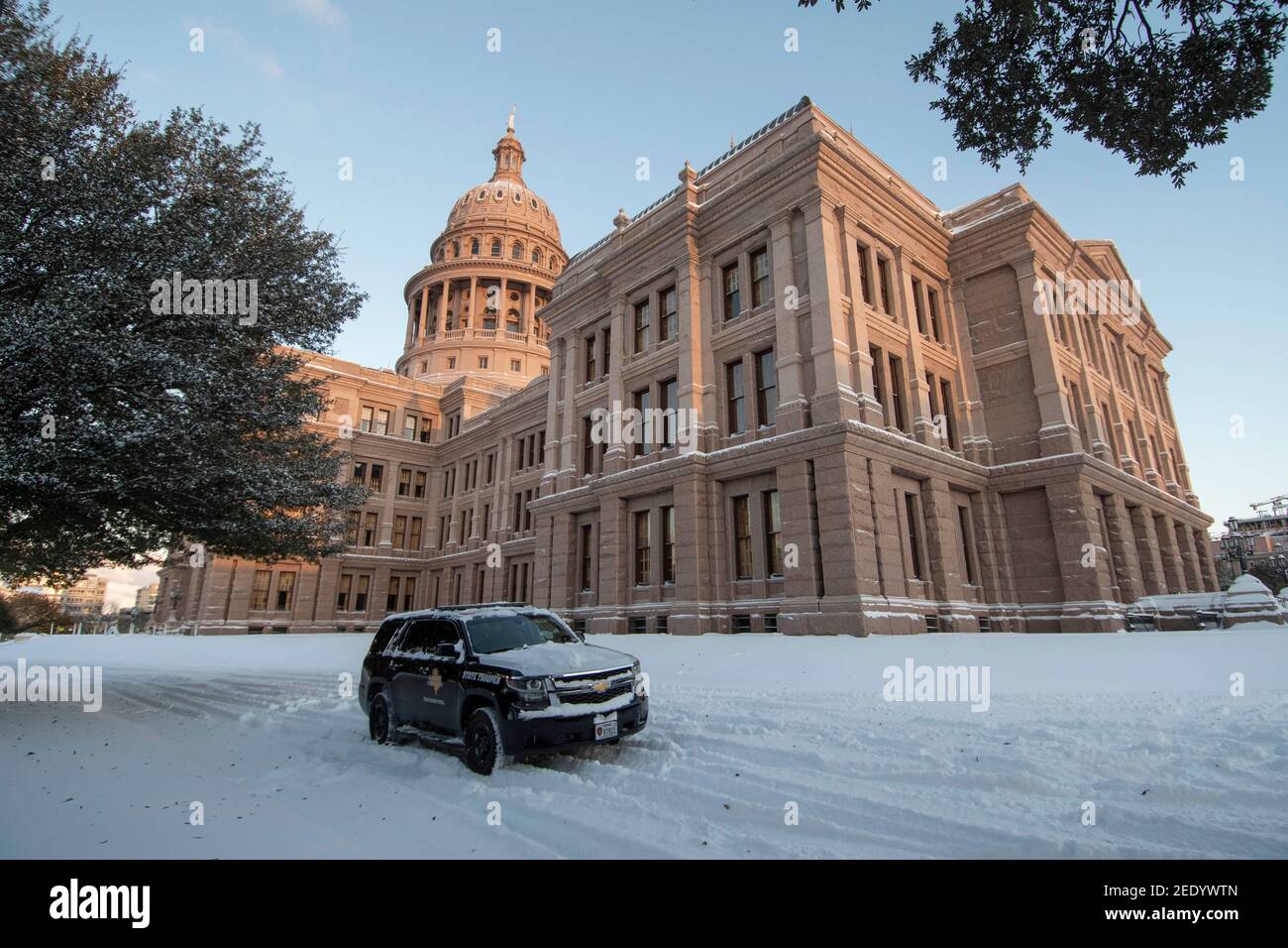 Austin, Texas USA Feb 15, 2021: A Dept. of Public Safety vehicle guards the east entrance of the Texas Capitol Monday morning after an overnight winter storm blew into central Texas dropping 6-7 inches of snow. The accompanying frigid weather wreaked havoc on the state's electricity grid, causing massive power outages to millions of customers across the state. Credit: Bob Daemmrich/Alamy Live News Stock Photo