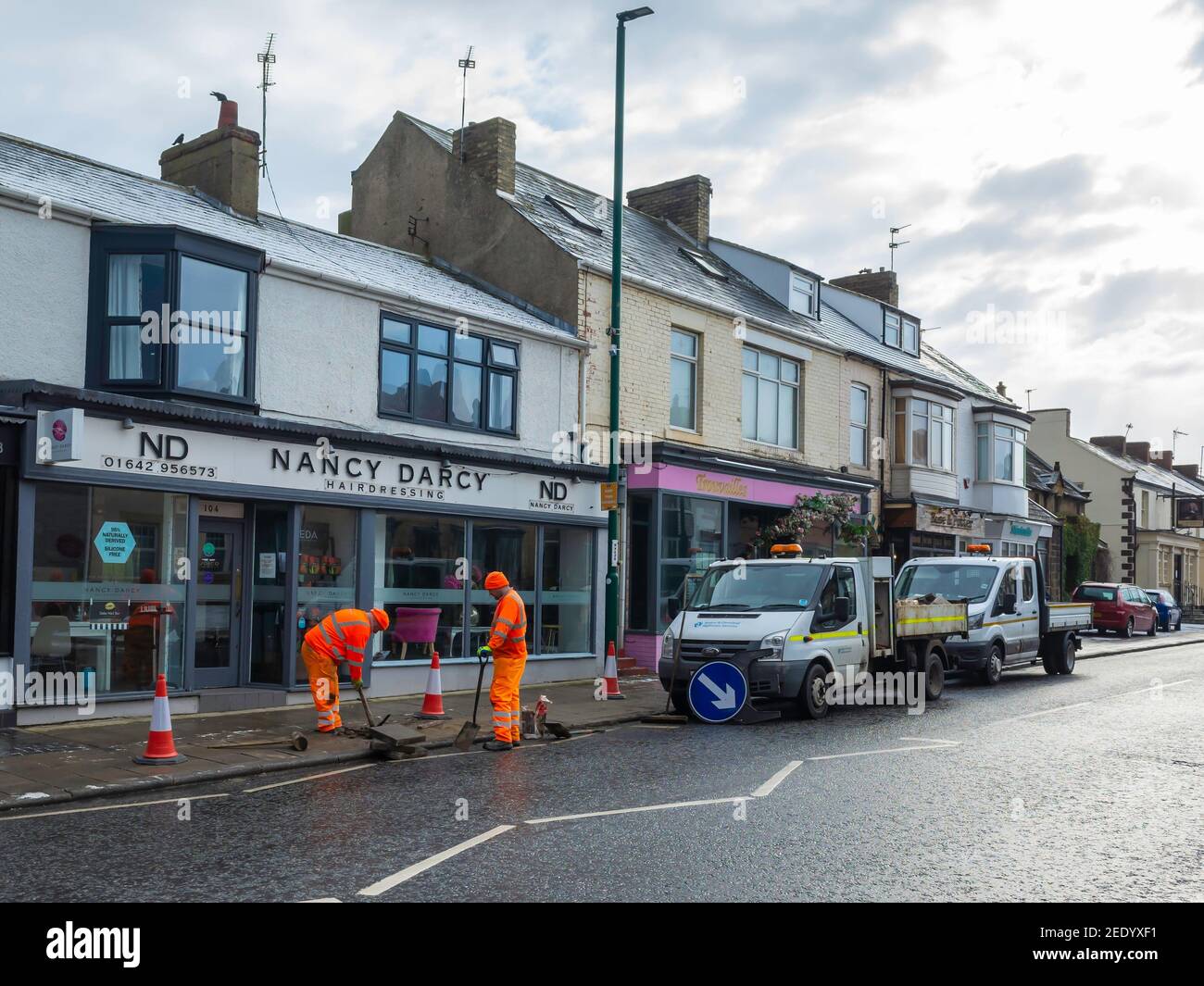 Redcar and Cleveland Council workers in distinctive orange overalls excavating a pavement in Marske by the sea for repair of a drain. Stock Photo