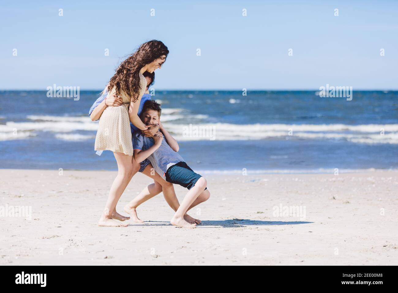 Mother and daughter playing with little brother by the sea. Family vacation. Summer break. Stock Photo