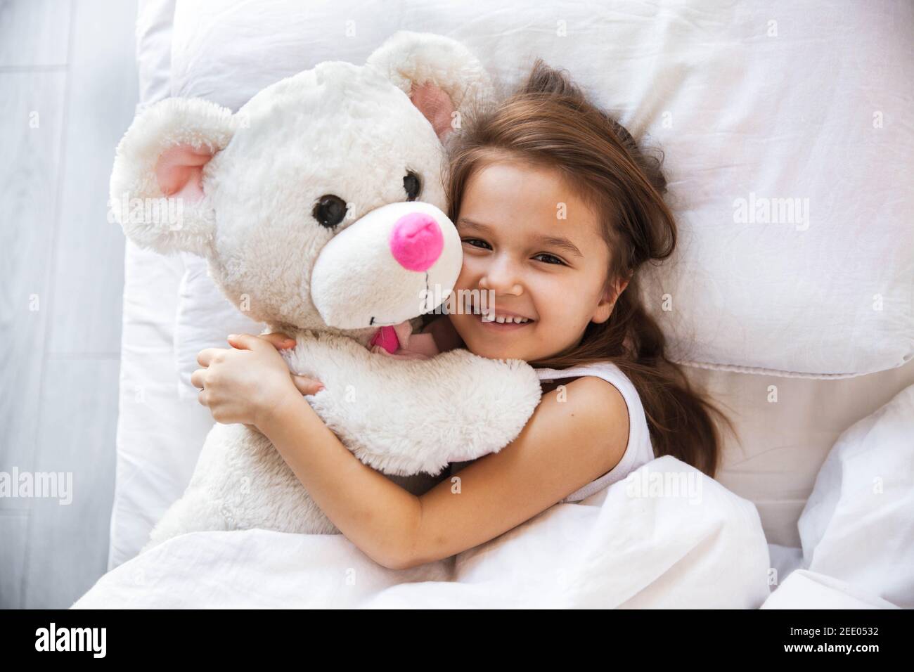beautiful little girl hugging her teddy bear in bed Stock Photo - Alamy