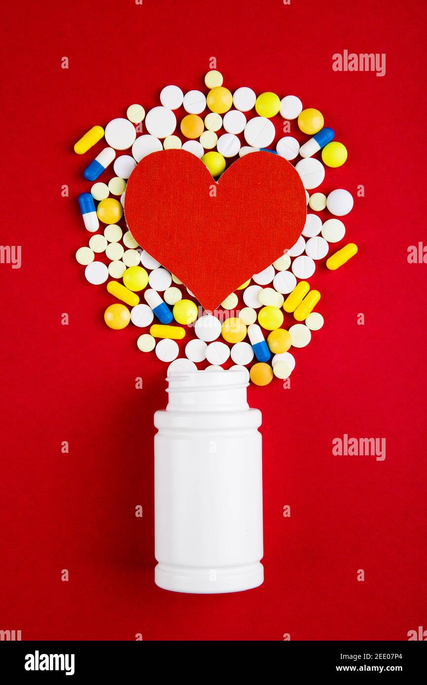 Heart Shape with a Pills on the Red Background closeup Stock Photo