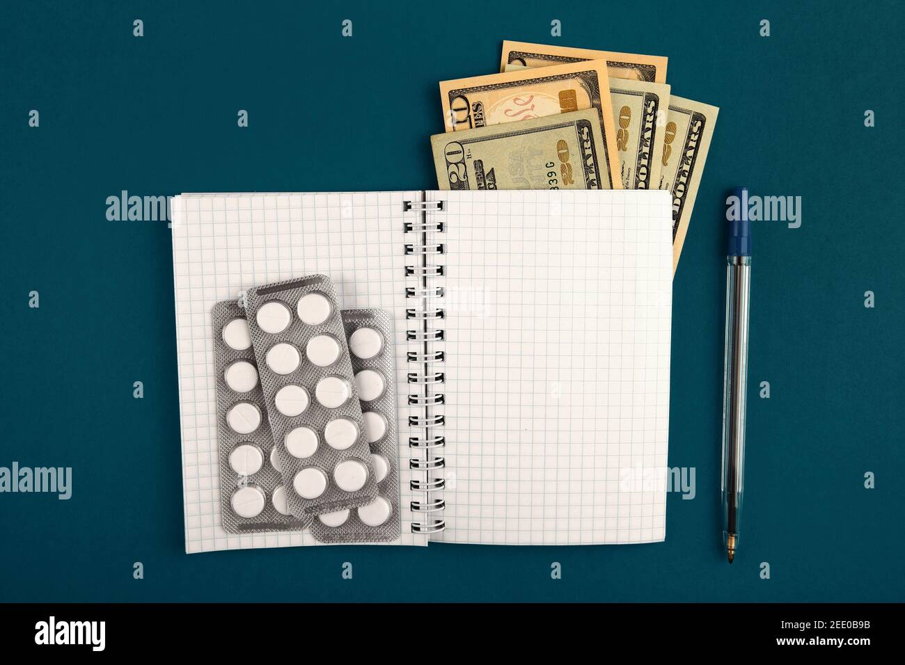 Writing Pad with a Money and the Pills on the Green Paper closeup Stock Photo