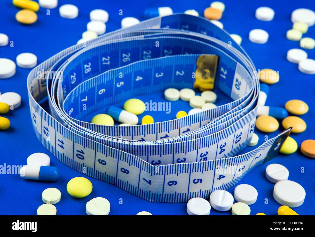 Scattering Pills with a Tape Measure on the Blue Paper Background closeup Stock Photo