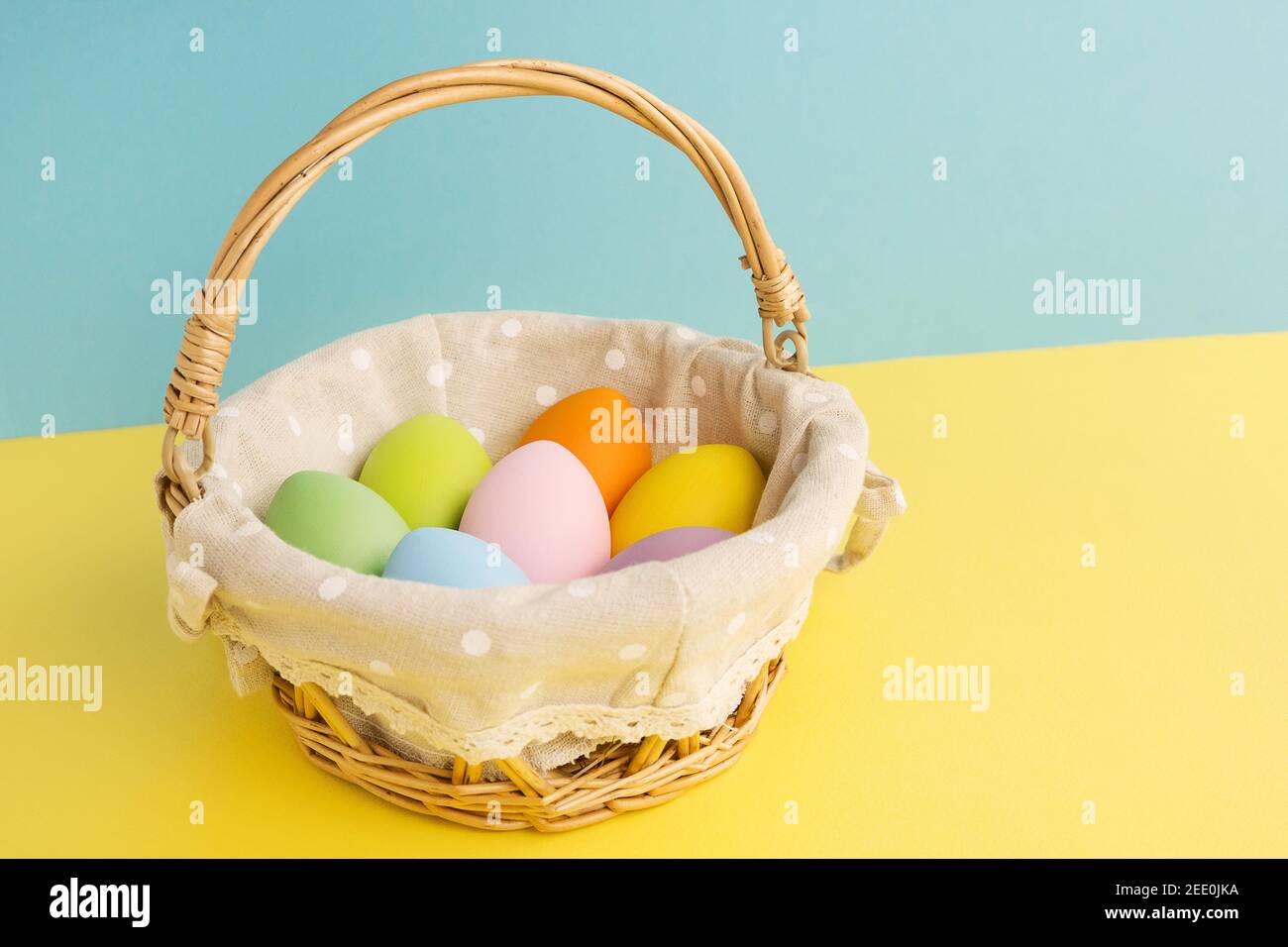 Basket with Easter colorful eggs on yellow blue background. Happy Easter concept Stock Photo