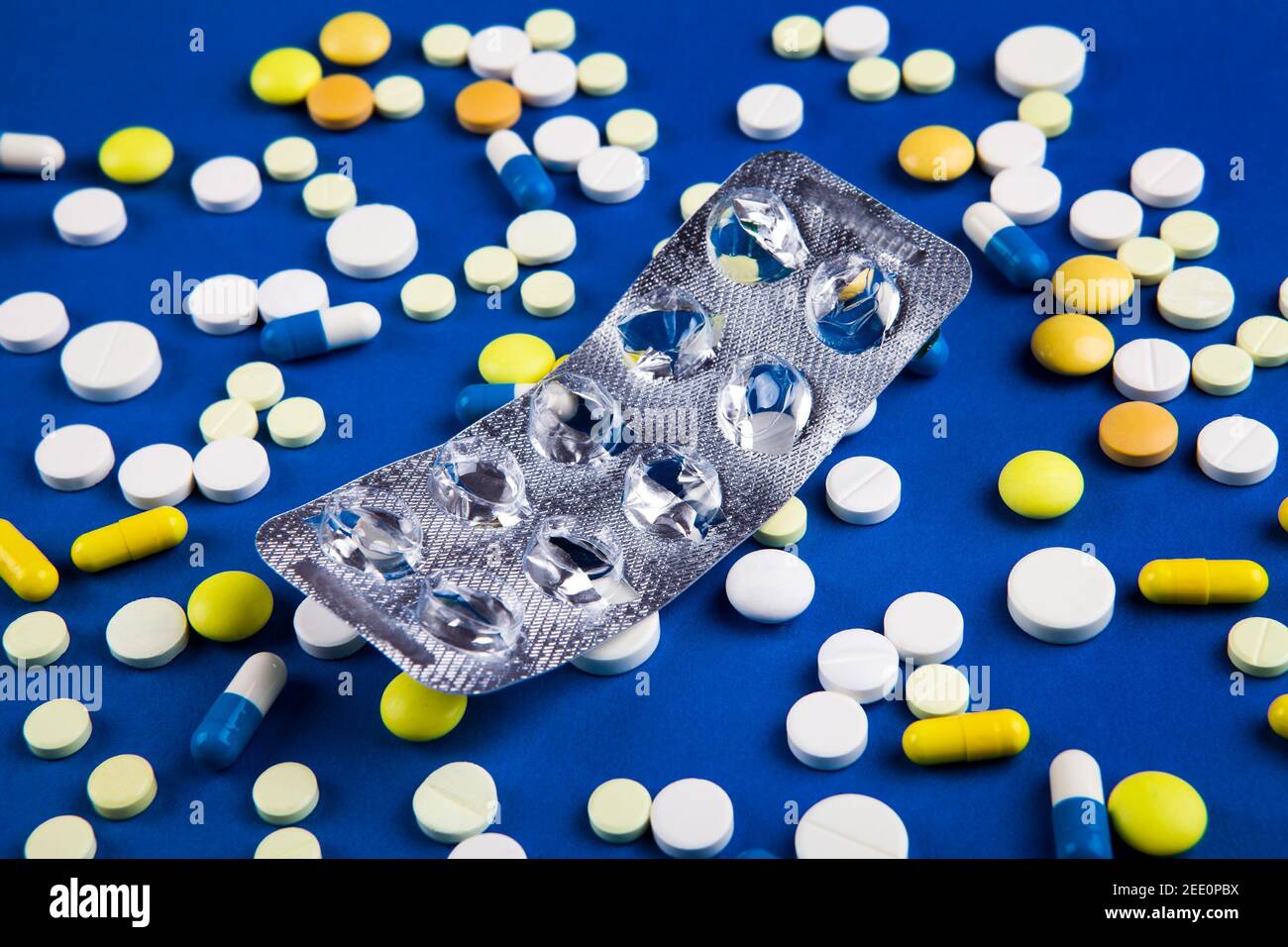 Empty Pack on the Scattering Pills and Blue Paper Background Stock Photo