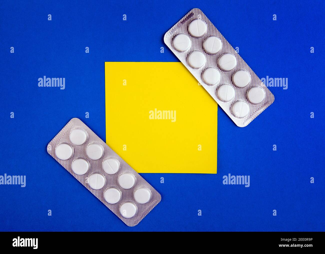 Pills and Empty Yellow Paper on the Blue Cardboard Background Stock Photo