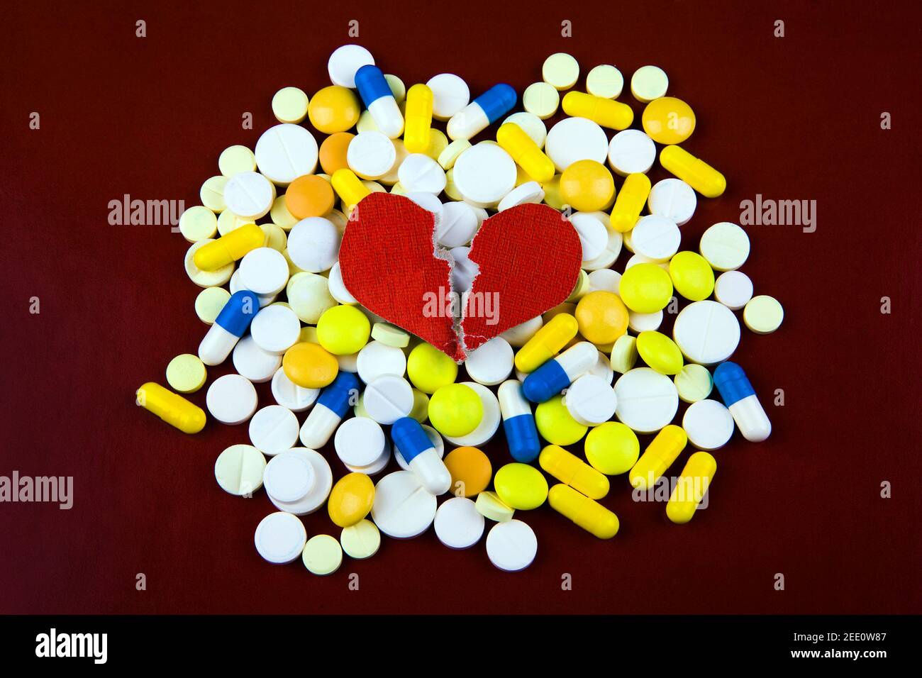 Broken Red Heart Shape with a Pills on the Paper Background Stock Photo