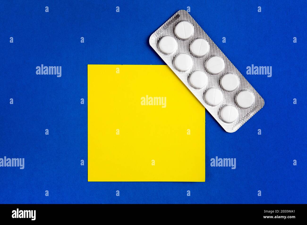 Pills and Empty Yellow Paper on the Blue Cardboard Background Stock Photo
