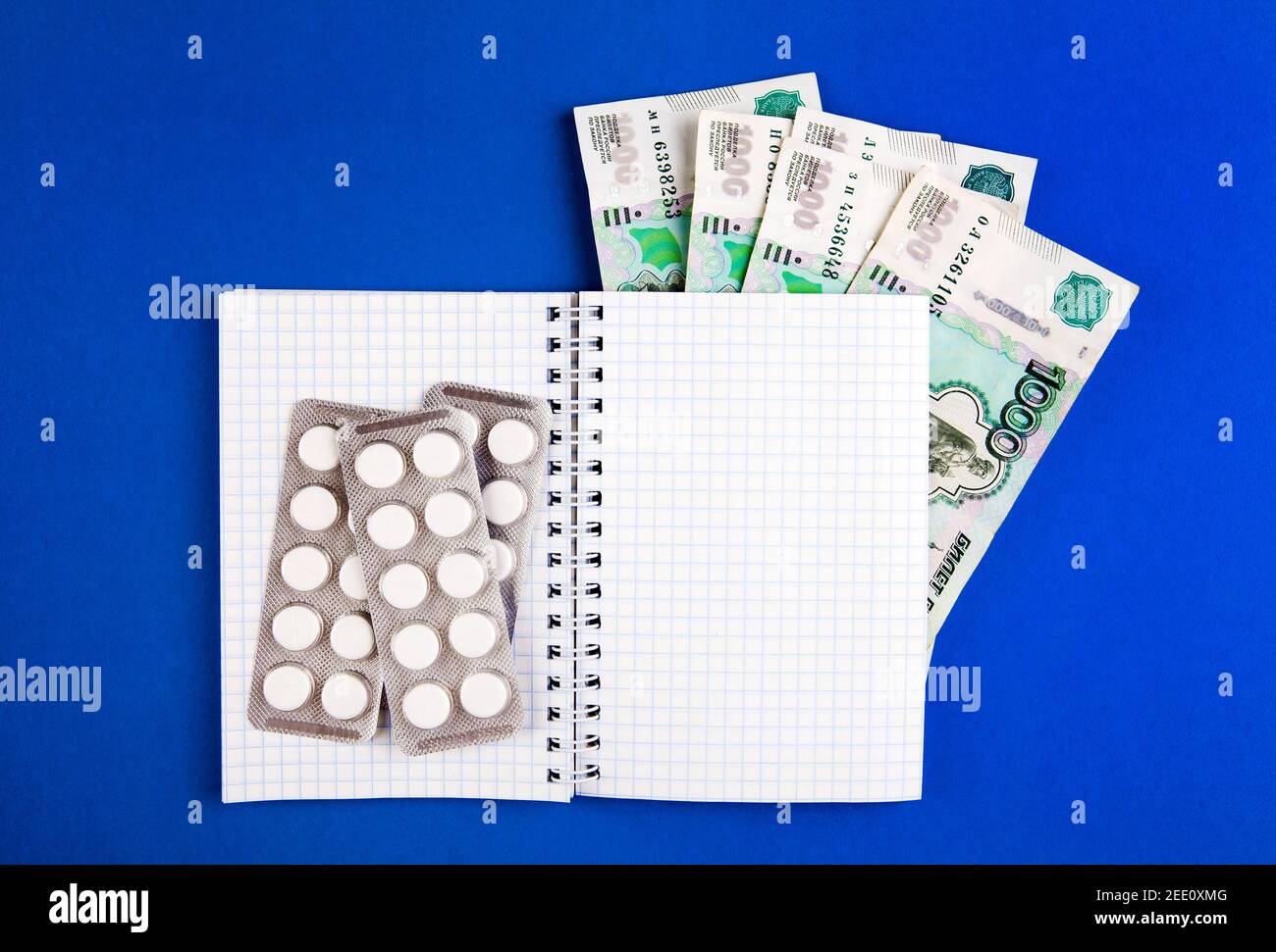 Writing Pad with a Russian Rubles and the Pills on the Blue Paper closeup Stock Photo