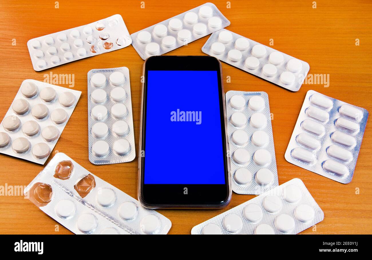 Mobile Phone with a Pills on the Wooden Table closeup Stock Photo