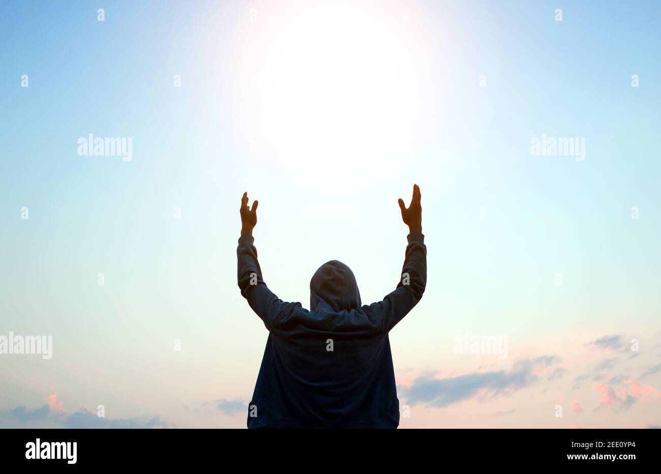 Silhouette of a Man in a Hoodie with Hands Up on the Sky Background ...
