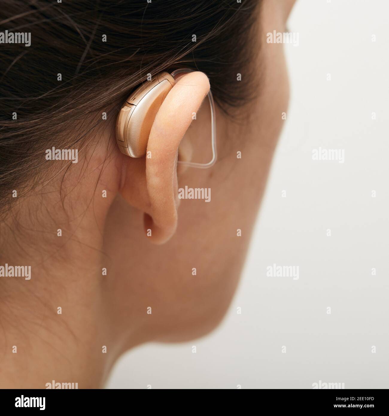 Woman wearing in latest generation hearing aid behind the ear. Hearing solution for adult people with deafness Stock Photo