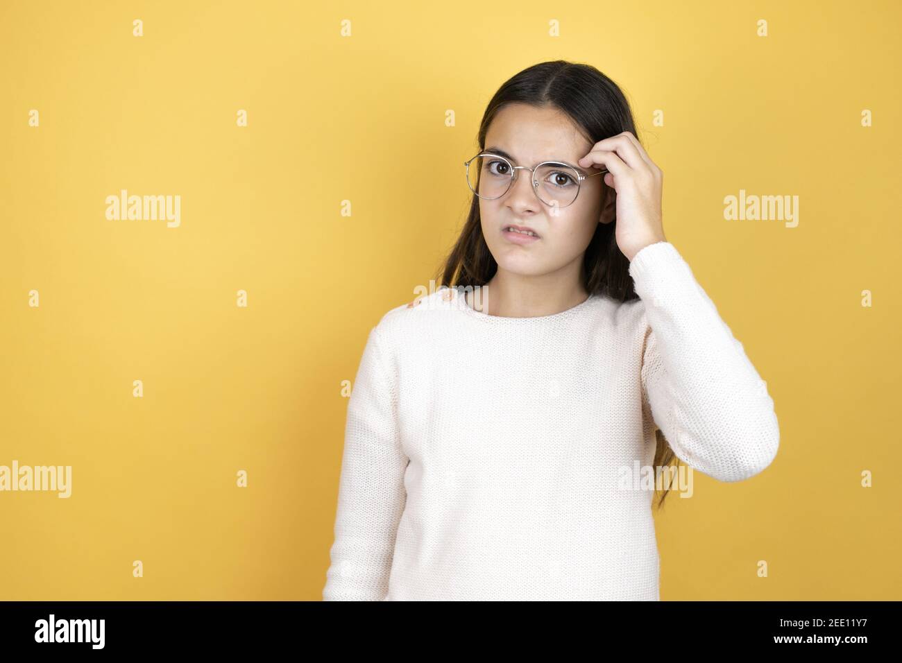 Beautiful child girl wearing casual clothes confuse and wonder about question. Uncertain with doubt, thinking with hand on head Stock Photo