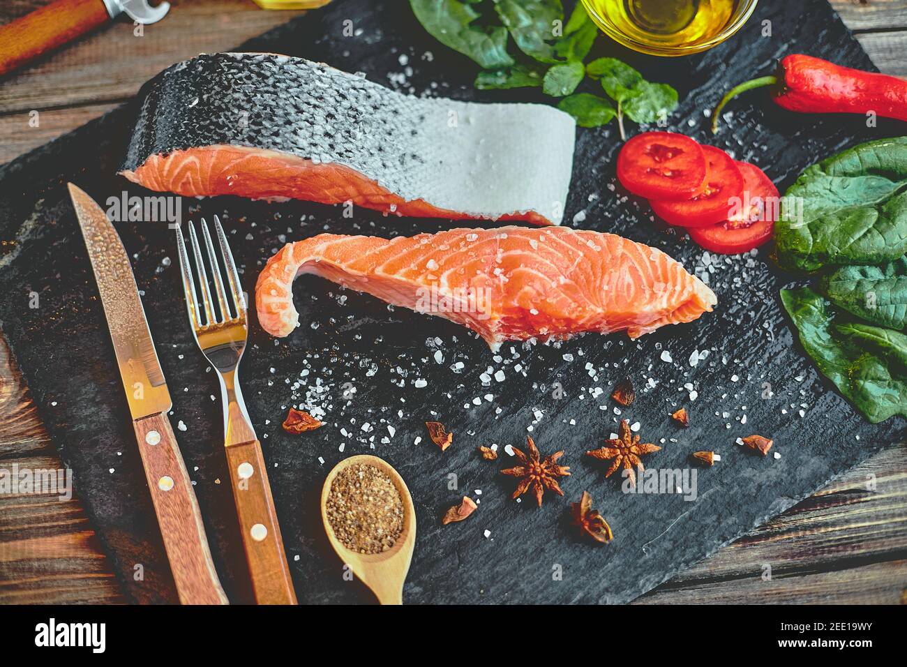 Raw salmon fillet and ingredients for cooking on a dark background ...
