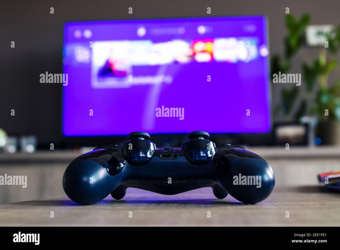 A portrait from behind a sony playstation 4 controller in front of a  television with the playstation home menu displayed on it. The PS4 video  game con Stock Photo - Alamy