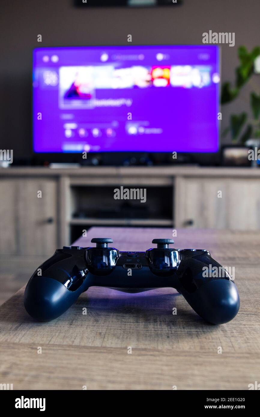 A vertical portrait of a sony playstation 4 controller in front of a  television with the playstation home menu displayed on it. The PS4 video  game con Stock Photo - Alamy
