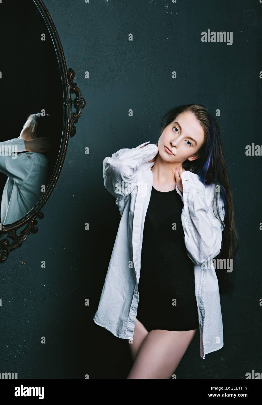 beautiful model wearing a white shirt in an old building with a mirror Stock Photo