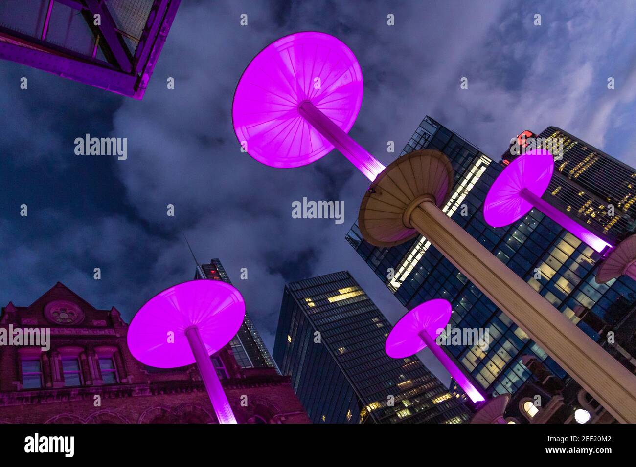 Illuminated pink mushroom lights at the entrance to Liverpool St Station against the background of the city at twilight - Stock Image