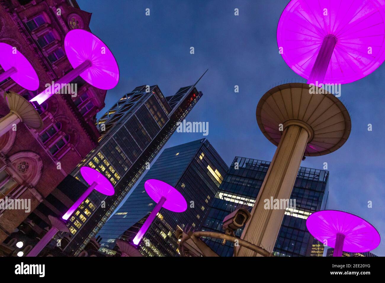 Illuminated pink mushroom lights at the entrance to Liverpool St Station against the background of the city at twilight - Stock Image