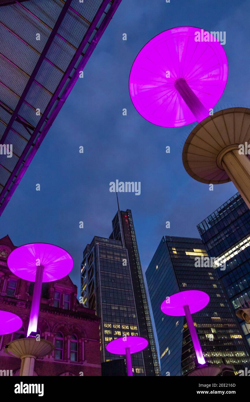 Illuminated pink mushroom lights at the entrance to Liverpool St Station against the background of the city at twilight - Stock Image