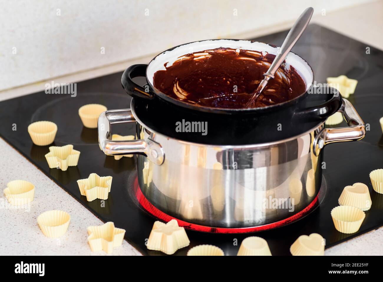 2 pot with water and melted chocolate on hot kitchen hob with variation of small white moulds