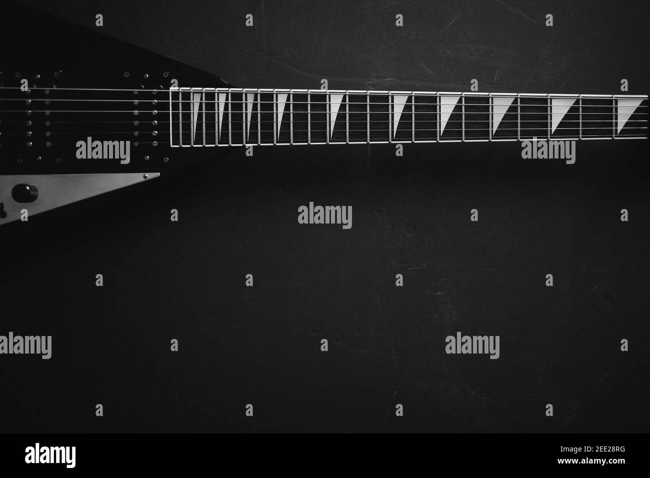 Black and white Top view crop shot of black V shape electric guitar on dark grunge background with copy space  Stock Photo