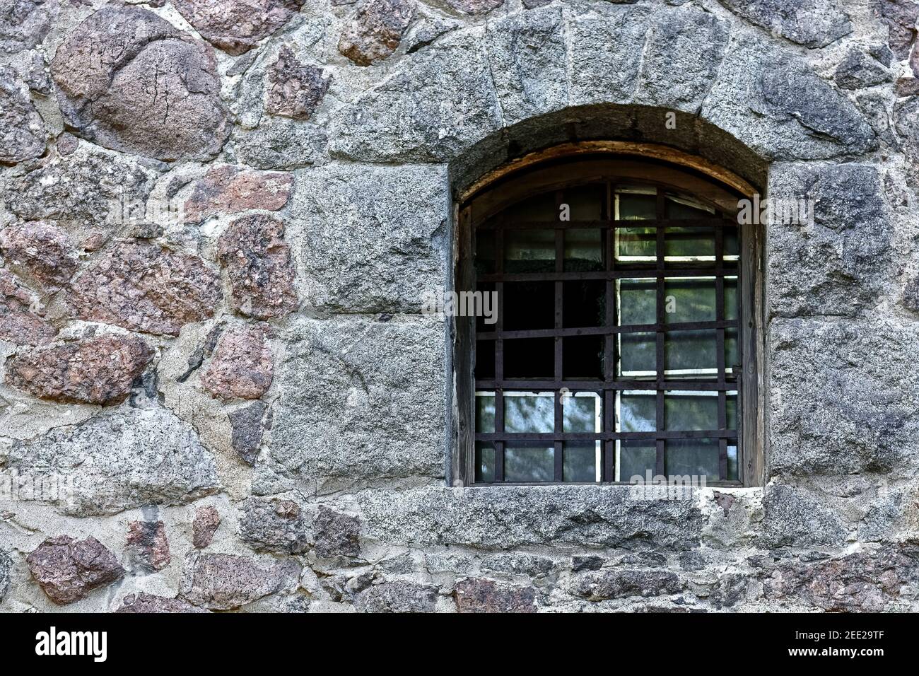 Arched window with iron bars on the stone wall of the old city prison ...