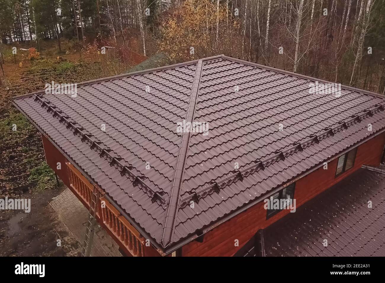 Modern roof made of metal. Corrugated metal roof and metal roofing. House with a brown metal