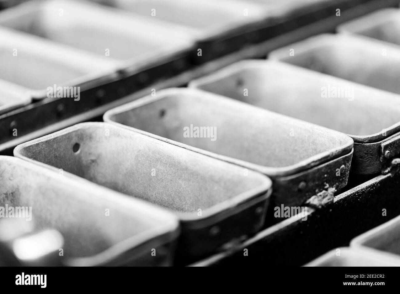 Industrial bakery automated line. Filling metal molds for baking bread. Stock Photo