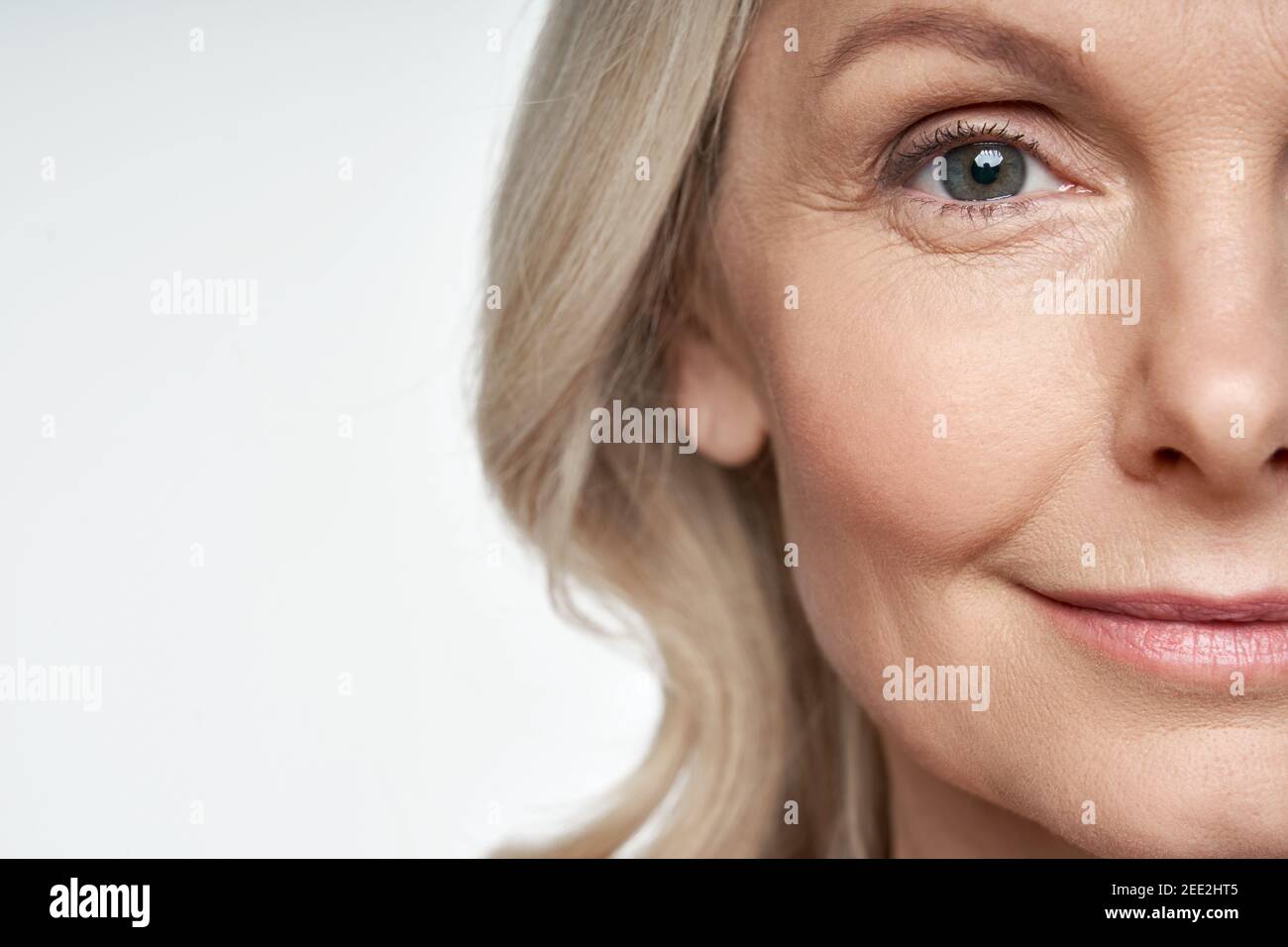 50s mid aged woman looking at camera. Anti age skin care. Half face crop Stock Photo