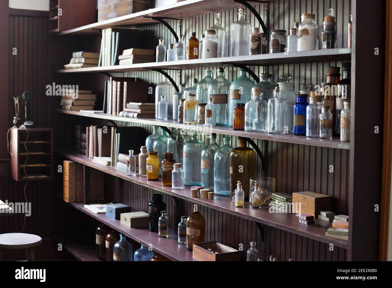 Antique bottles of different colors on a shelf. Stock Photo