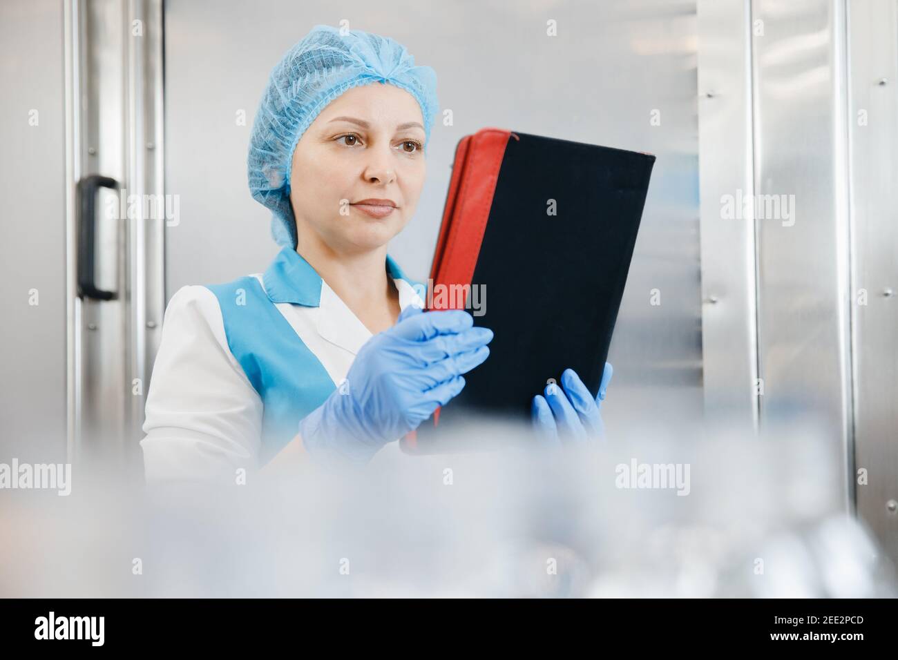 Female factory worker with computer checking production line drinks ...