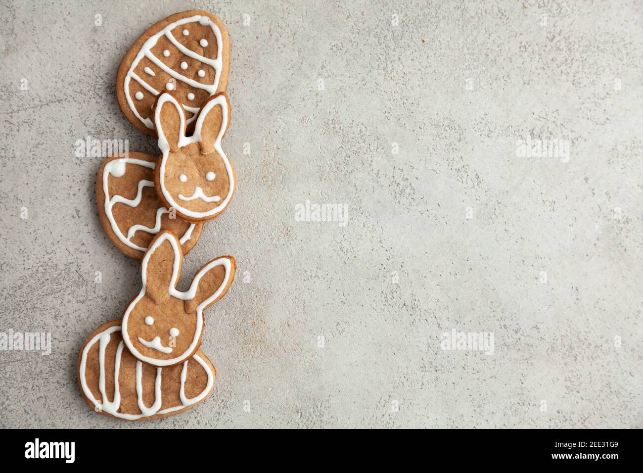 Easter decorated cookies in the shape of a bunny and eggs are laid out in a row on a gray background. Top view Stock Photo