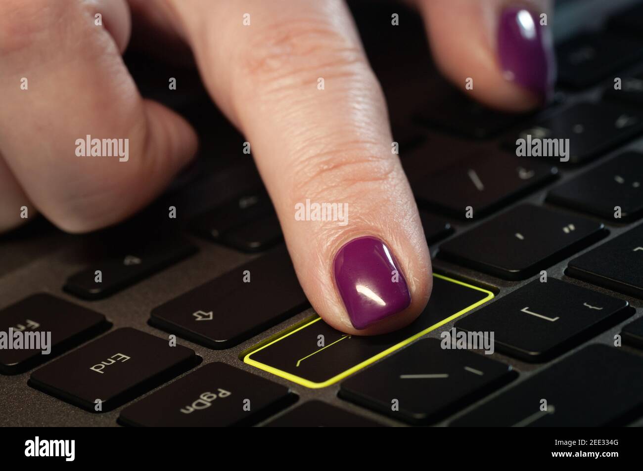 Close up woman's finger pressing enter button on the laptop keyboard. Stock Photo