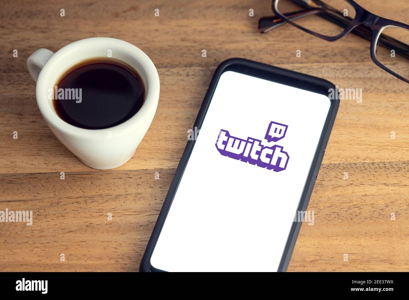 Galicia, Spain; february 15, 2021: Twitch logo on Smart phone screen on desk with eyeglasses and cup of coffee on wooden table Stock Photo